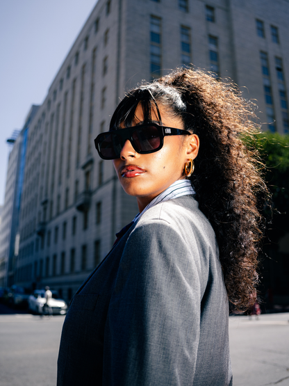 Dimas black frame black lense Eyewear unisex sunglasses collection modern fashion frames South African eyewear brand 1 studio image female model outside