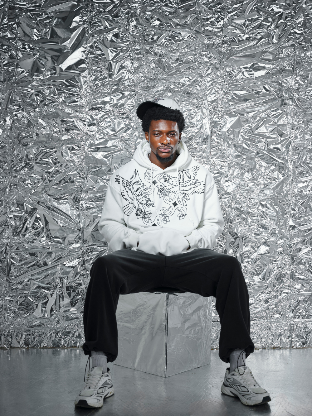 Empire white oversized graphic hoodie at unseen grail. local brands south africa. streetwear. men and women. studio image close up front male model sitting