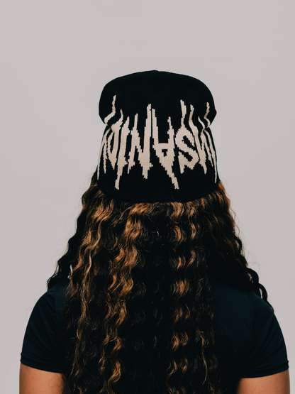 Insanidy knitwear black beanie at unseen grail. local brands south africa. streetwear. men and women. studio image female model behind