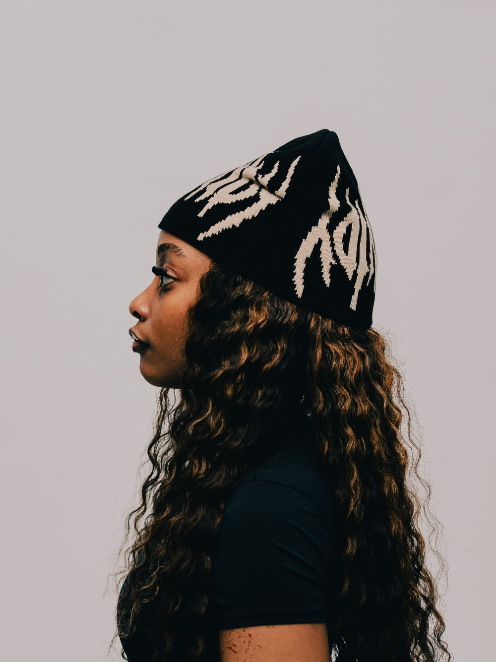 Insanidy knitwear black beanie at unseen grail. local brands south africa. streetwear. men and women. studio image female model side
