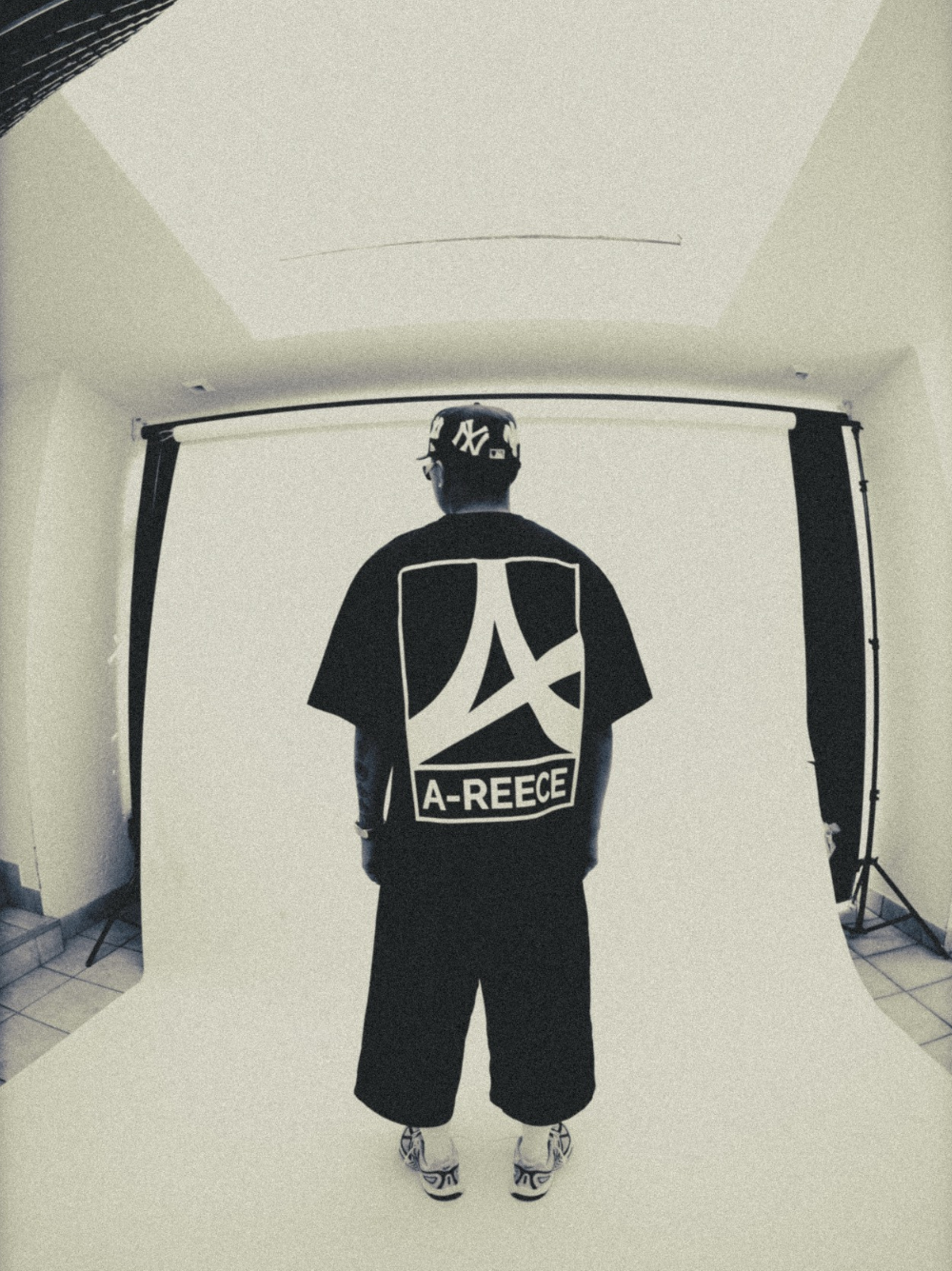 Mercha black oversized graphic vest at unseen grail. local brands south africa. streetwear. men and women. studio image behind a reece music in studio